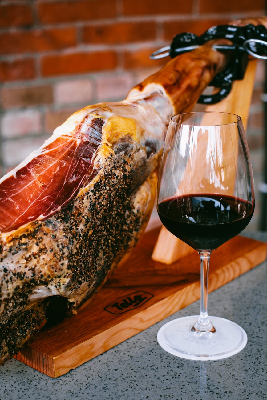 photo of a glass of wine beside jamon